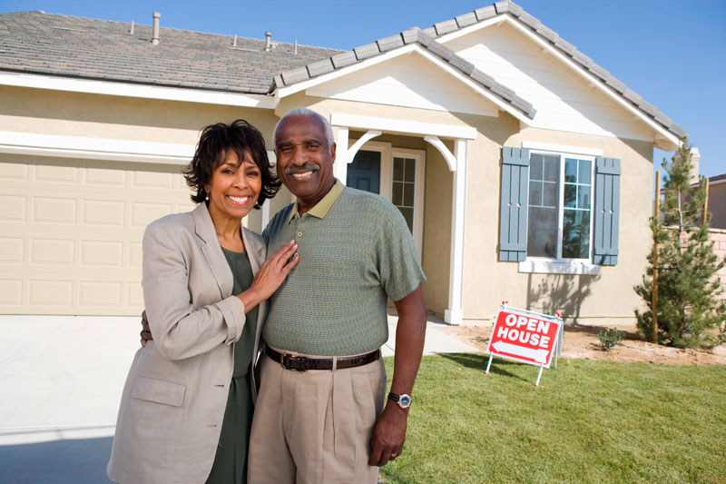 An older couple in front a home for sale