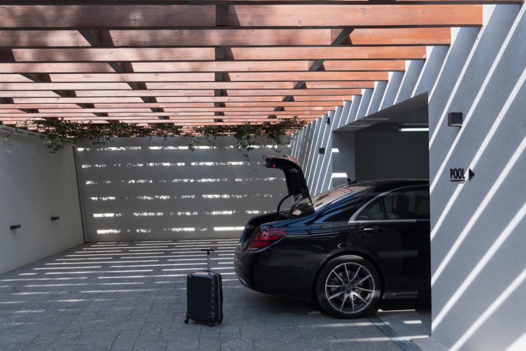 A photo of a suitcase standing next to a car in a luxury garage to illustrate How wide is a two-car garage