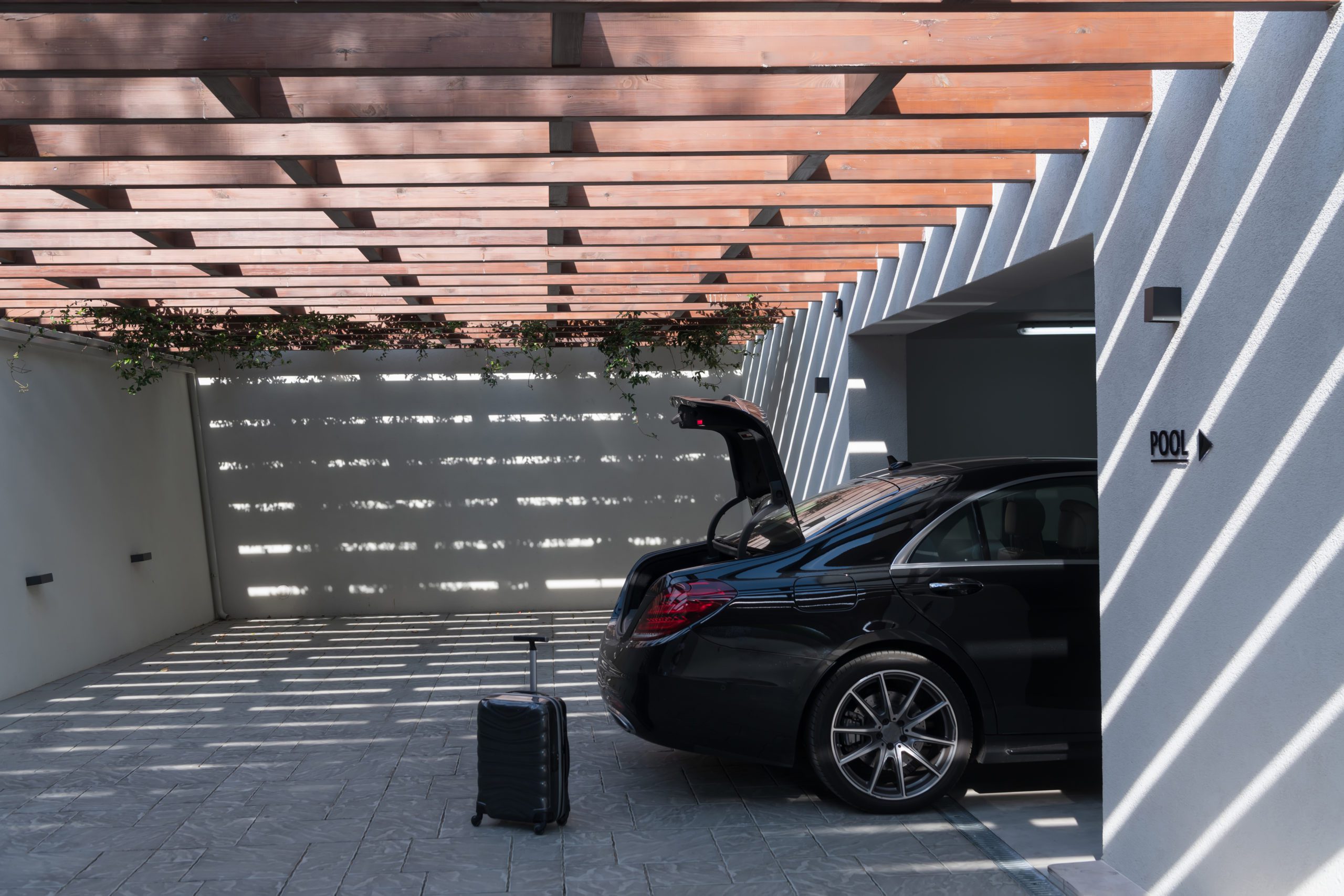 A photo of a suitcase standing next to a car in a luxury garage to illustrate How wide is a two-car garage