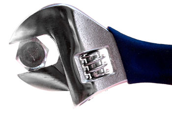 A wrench is seen on a bolt, such as the type used to fix garage door alignment.